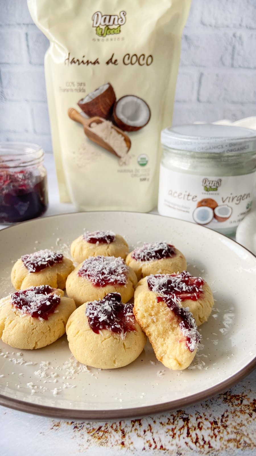 Bizcochitos redondos de harina de coco decorados con mermelada de frutos rojos y coco rallado
