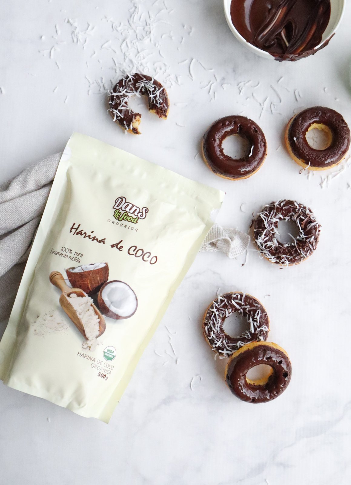 Donas redondas horneadas bañadas en chocolate negro y espolvoreadas con coco rallado