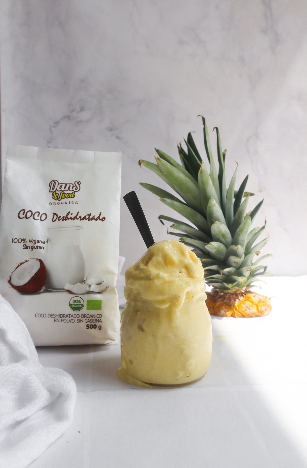 Helado cremoso amarillo de piña colada con leche de coco servido en copa