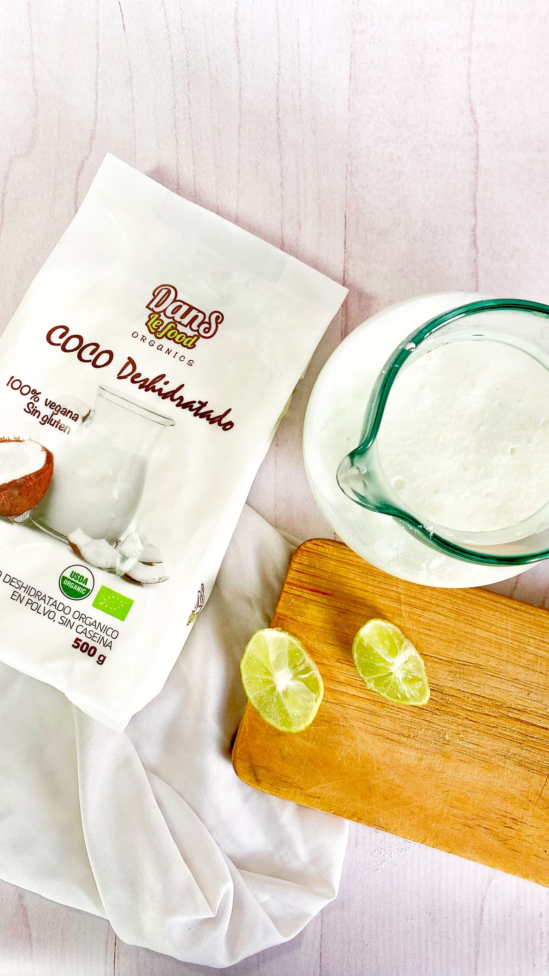 Jarra de limonada de coco espumosa recién licuada junto a la leche de coco en polvo