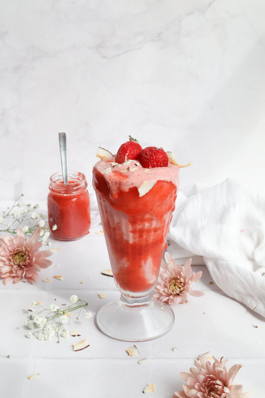 Malteada cremosa de fresa y coco servida en copa decorada con coulis rojo
