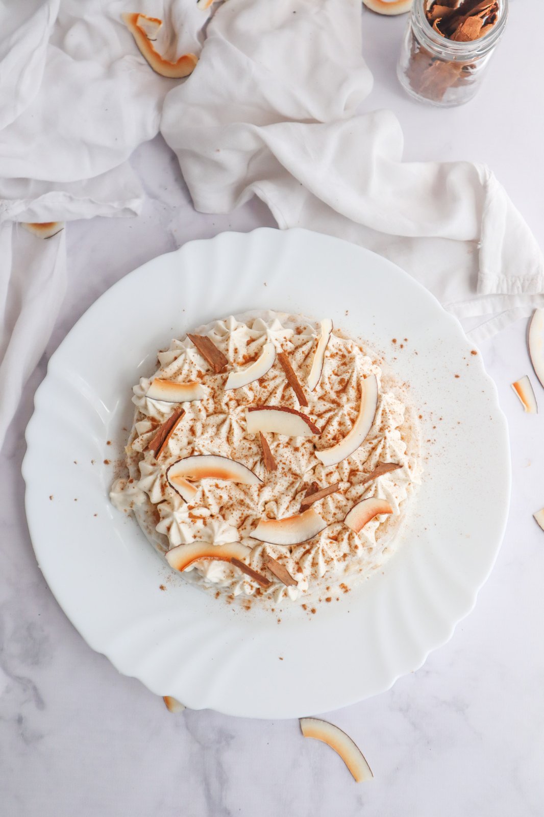 Torta tres leches de coco con frosting blanco, espolvoreada con canela y chips de coco