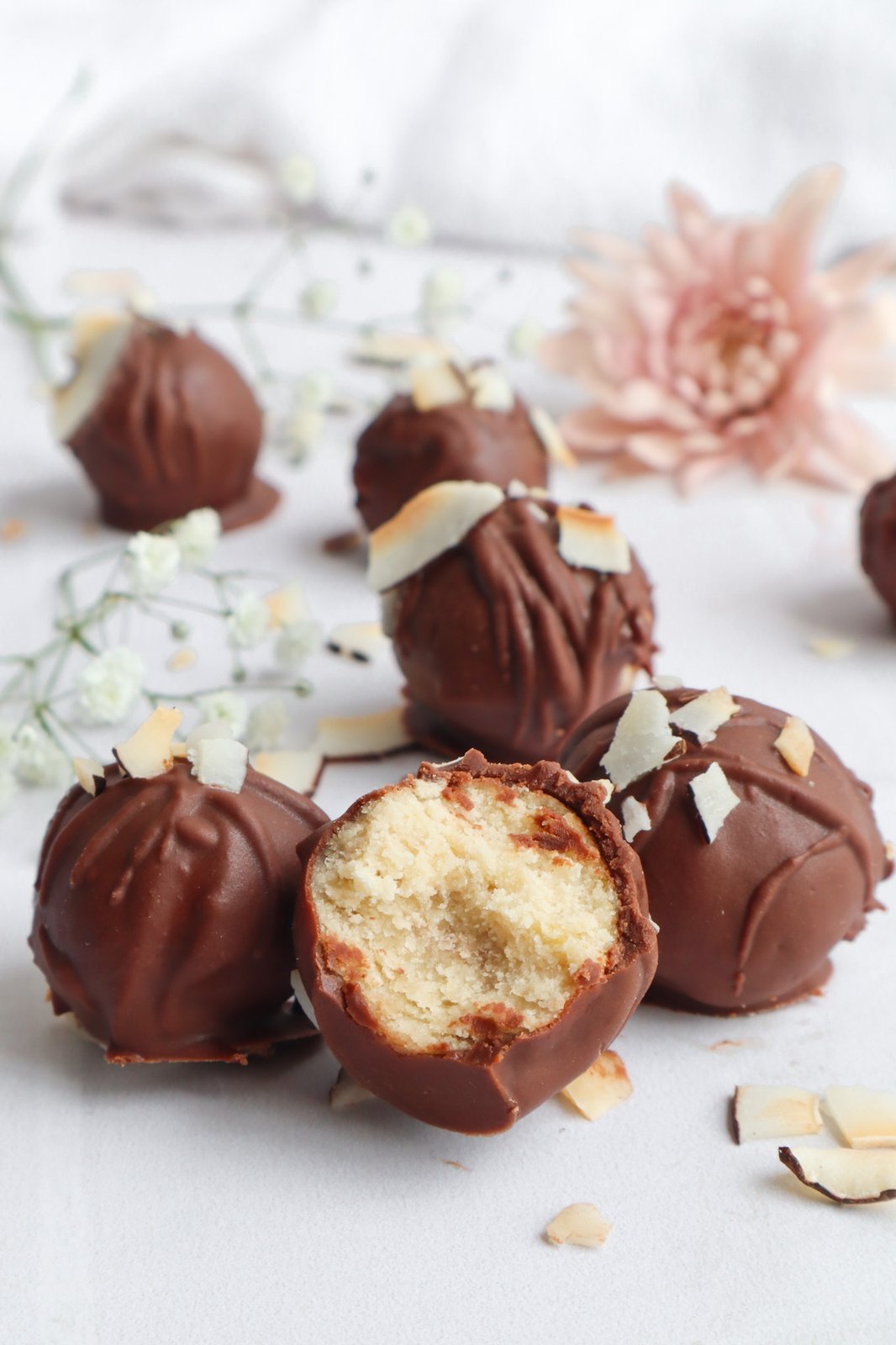 Trufas redondas de chocolate y coco recubiertas con chips de coco rallado sobre tabla de madera