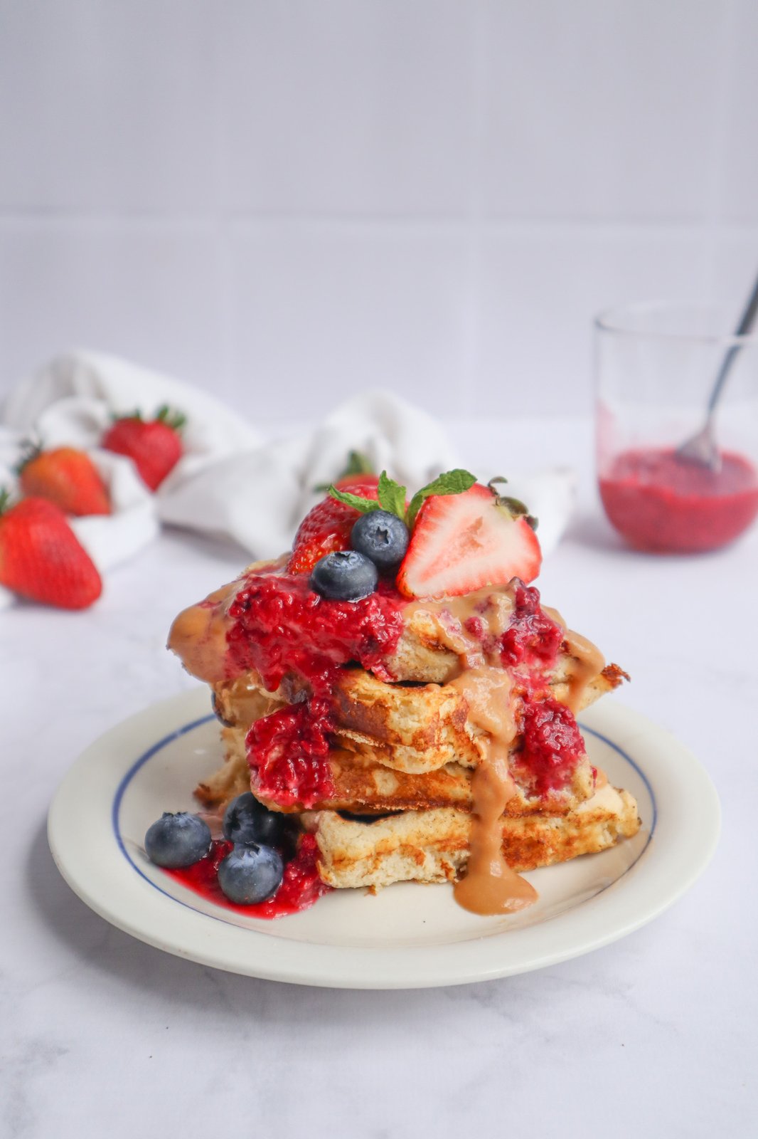 Stack de waffles de coco con mermelada de frutos rojos, arándanos, fresas y caramelo de panela sobre plato blanco